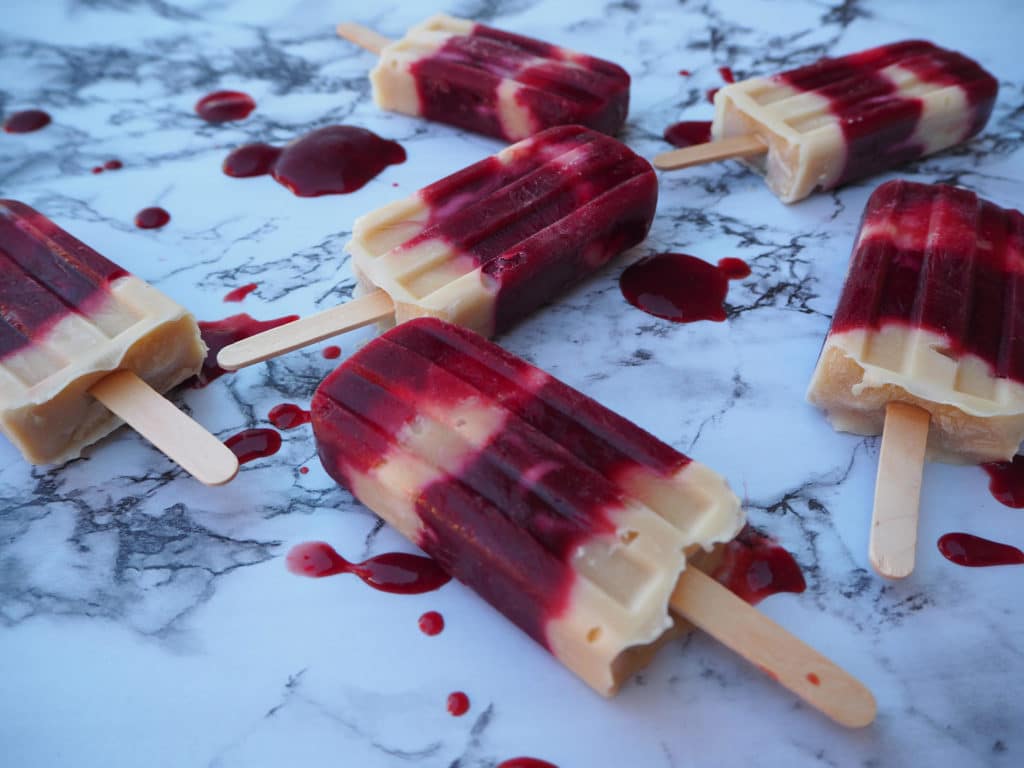 Close up of blood plum and cashew yogurt popsicles on marble board