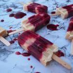 Close up of blood plum and cashew yogurt popsicles on marble board