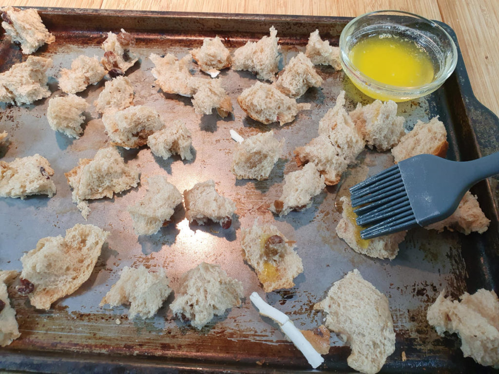 Brushing butter onto hot cross bun pieces