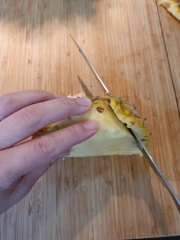 Slicing fresh pineapple skin off