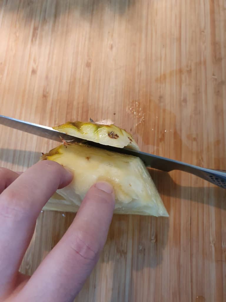 Slicing fresh pineapple skin off