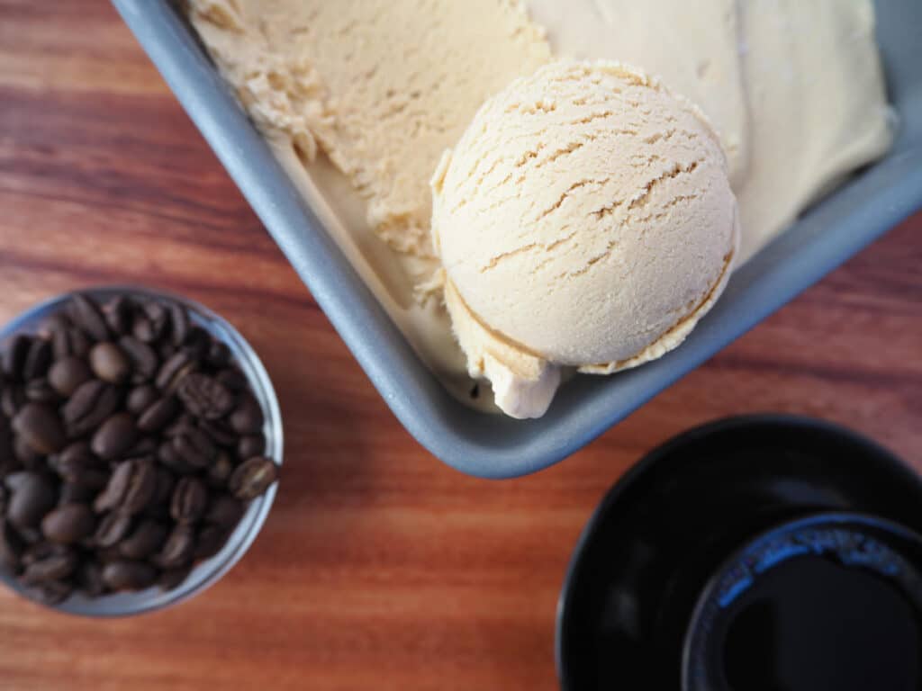 No churn coffee ice cream scoop in pan with bean and coffee