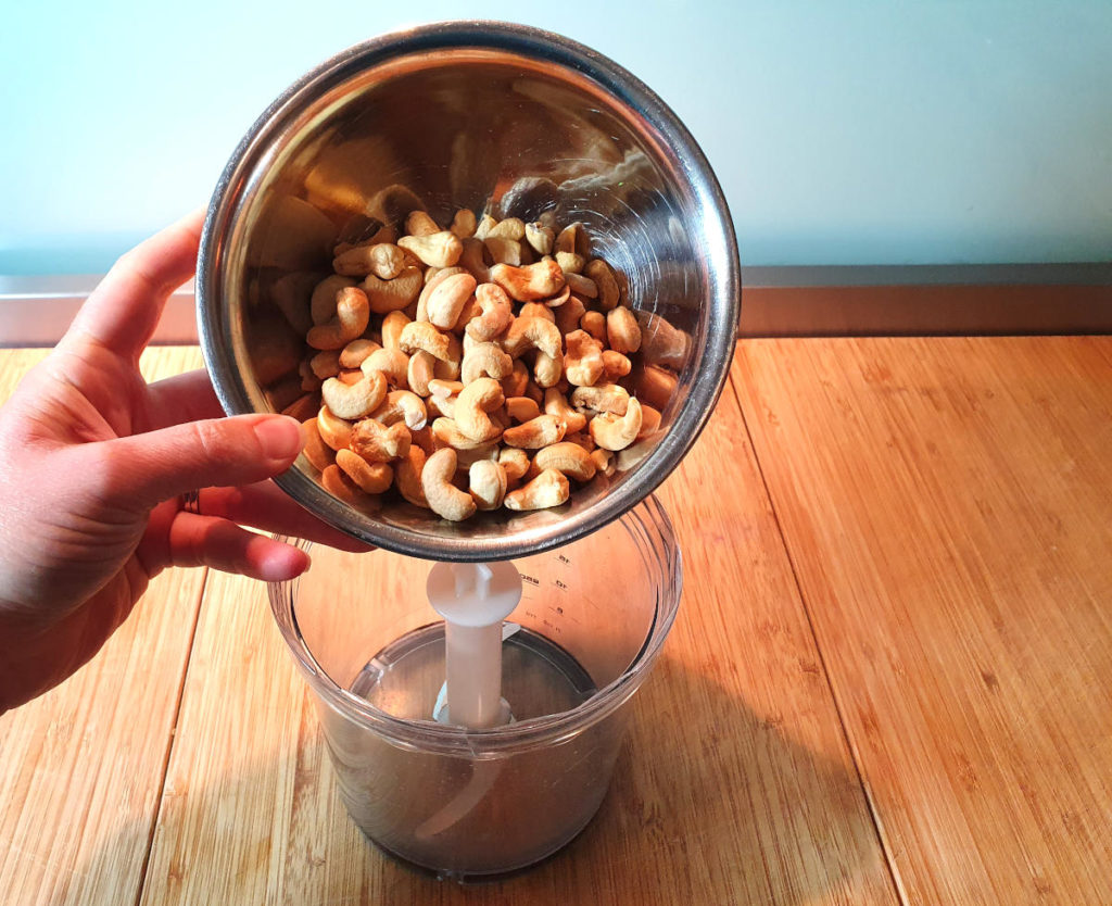 adding cashews to chopping bowl