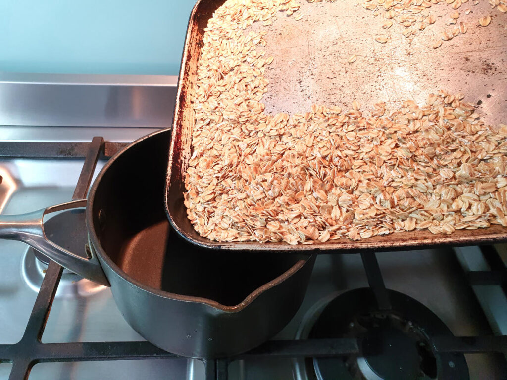 adding roasted oats to saucepan