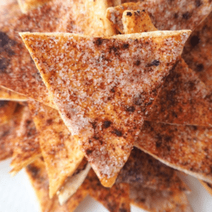 close up of pile of cinnamon sugar pita chips on a while plate.