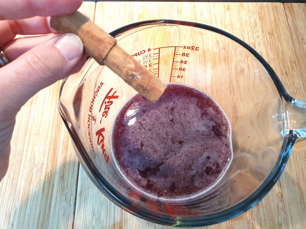 adding cinnamon stick to jug of sangria popsicle mix