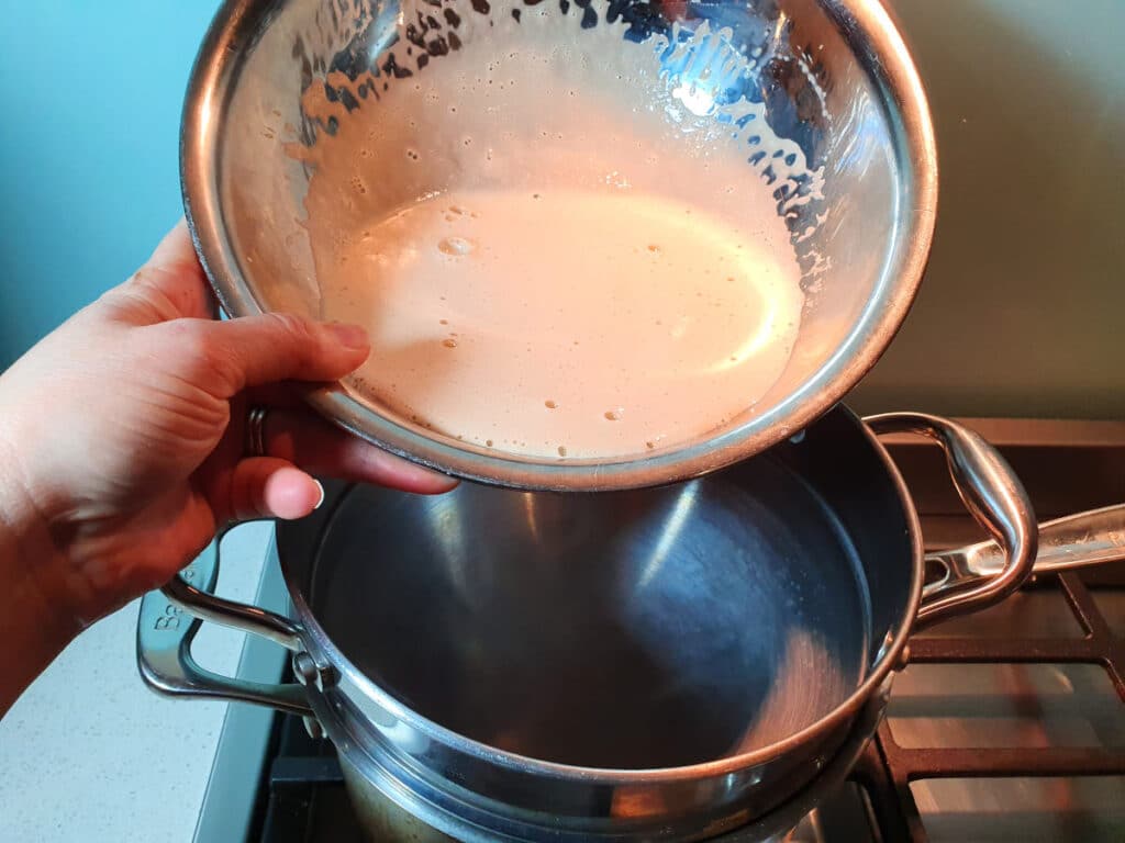 Adding milk, tea, sugar and egg yoke mix to double boiler on stove top