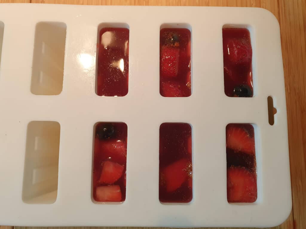 popsicle moulds filled with fruit and sangria popsicle mix