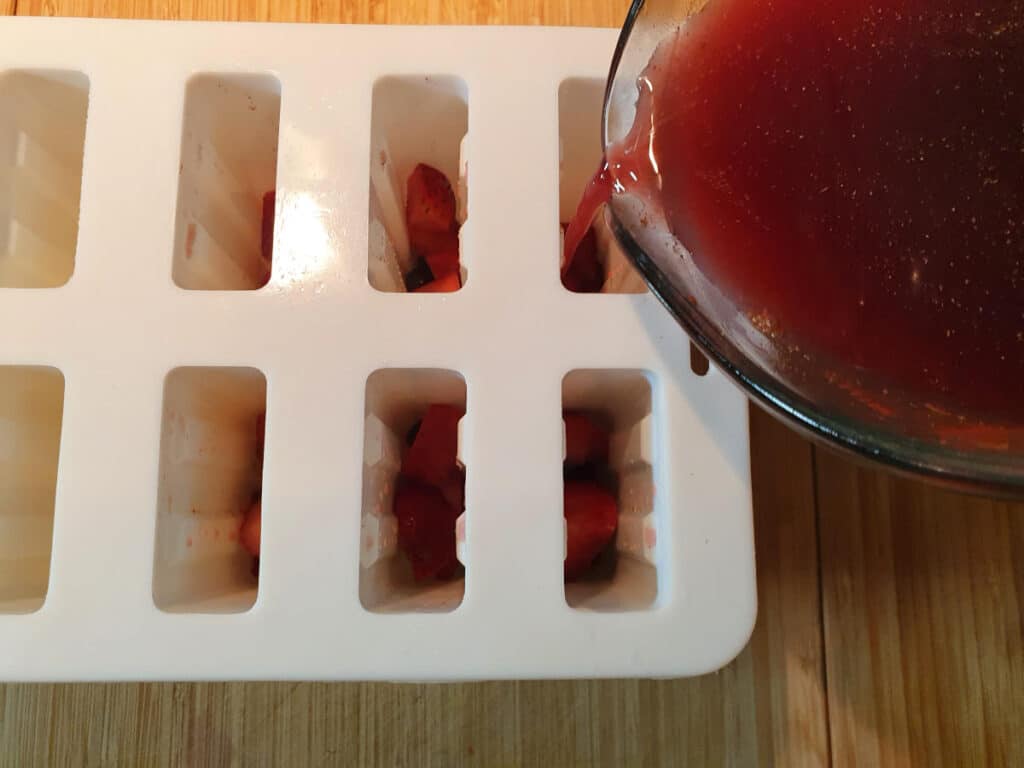 adding sangria popsicle mix to popsicle moulds