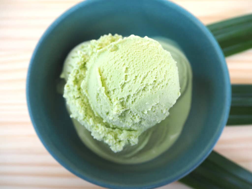 Pandan ice cream in green bowl on board with leaves in fan shape