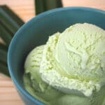 Pandan ice cream in green bowl on board with leaves in fan shape