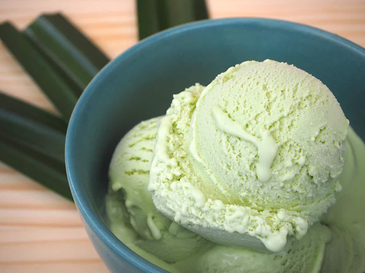 Pandan ice cream in green bowl on board with leaves in fan shape