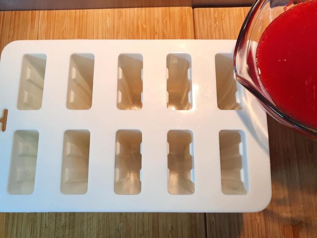 pouring popsicle mix into popsicle moulds