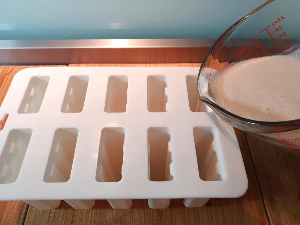 Pouring popsicle mix into popsicle moulds