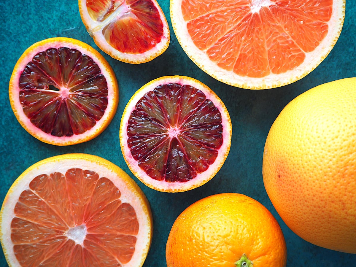 Ruby grapefruit and blood oranges, whole, segments and slices on a green background