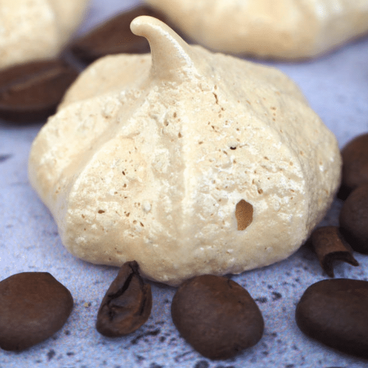 side view close up of coffee vegan meringues with coffee beans, on a grey background.