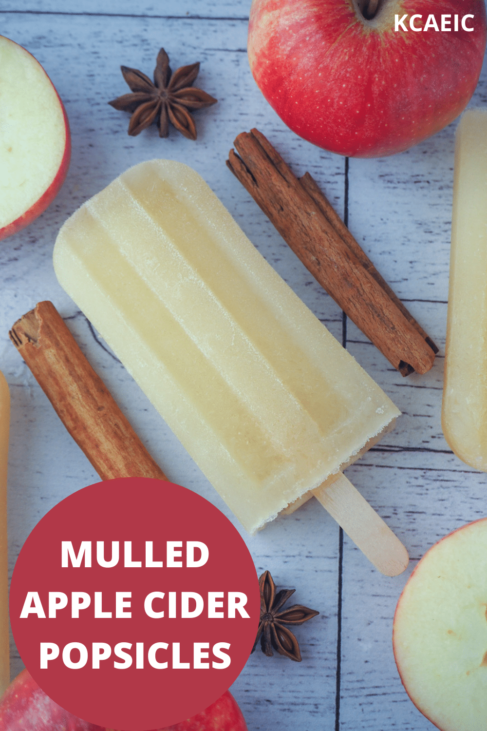 Top down view of mulled apple cider popsicle, with apple, apple star and star anise, with text overlay, mulled apple cider popsicles and KCAEIC.