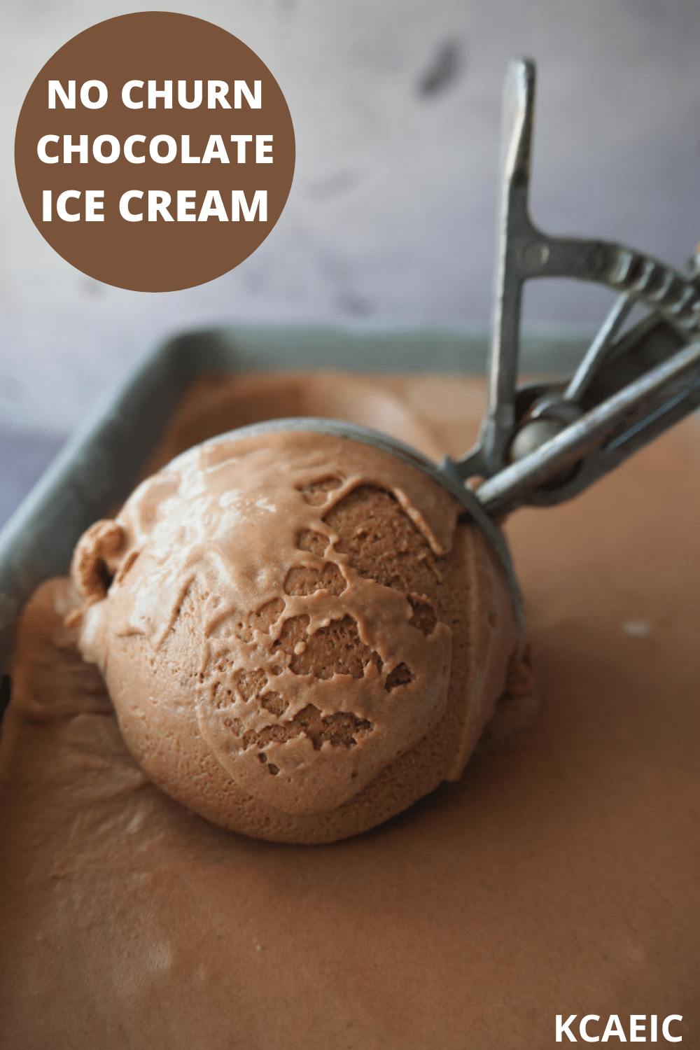 Close up of no churn chocolate ice cream in pan being scooped, with text overlay, no churn chocolate ice cream, KCAEIC, with grey back ground.