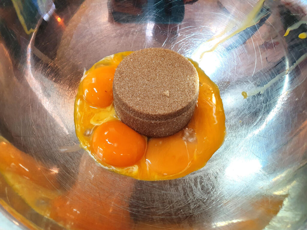 Pumpkin spice ice cream 14 Top down view of tightly packed brown sugar and four egg yokes in a metal bowl.