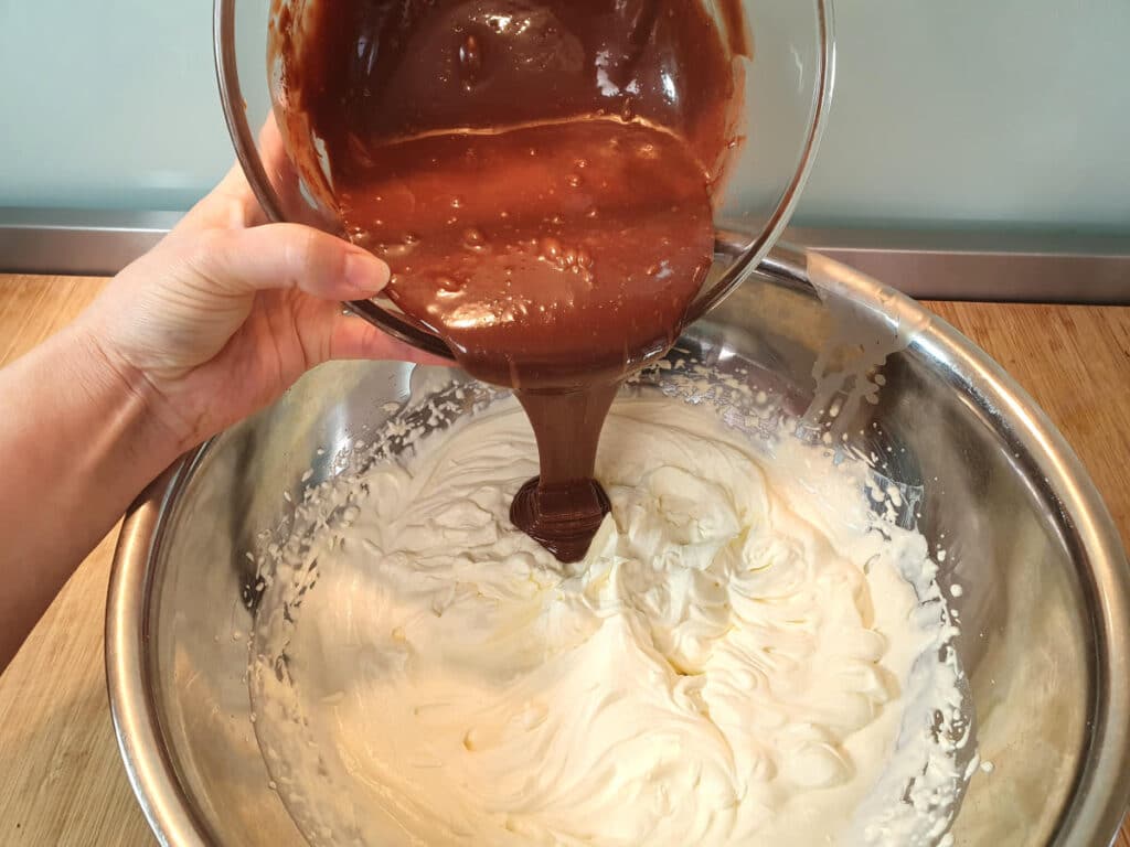 adding chocolate mix to large bowl of whipped cream.