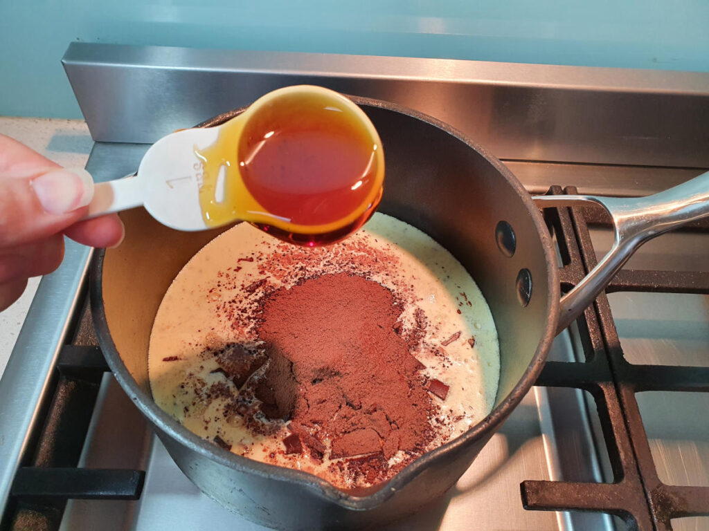 adding golden syrup to pot on stove with chocolate fudge sauce ingredients.