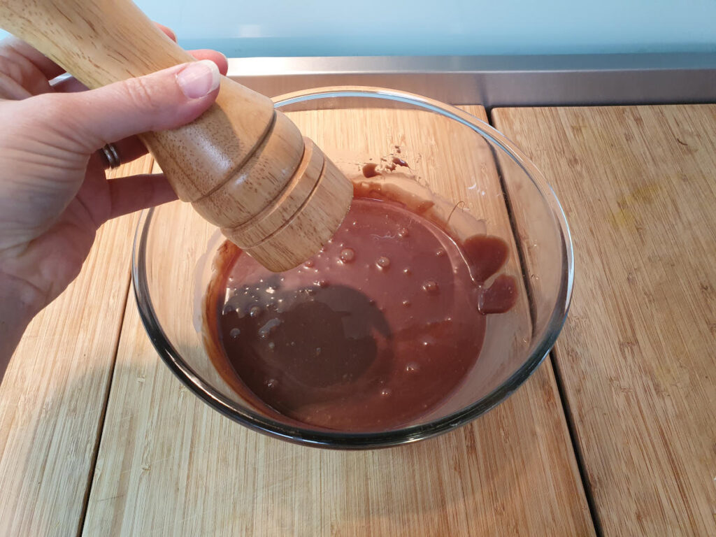No churn chocolate ice cream 6 adding salt from salt grinder to chocolate mix in a glass bowl.