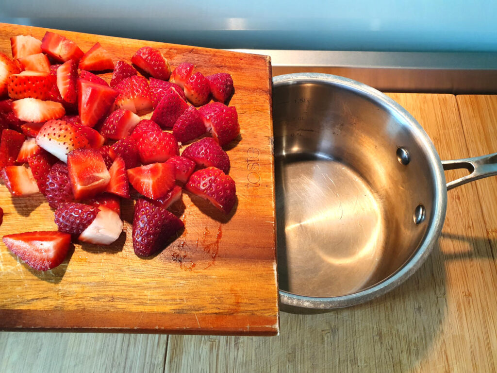 Strawberry compote (strawberry sauce) 5 adding chopped strawberries to pot.