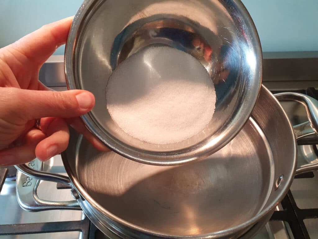 adding sugar to top of double boiler on stove top.