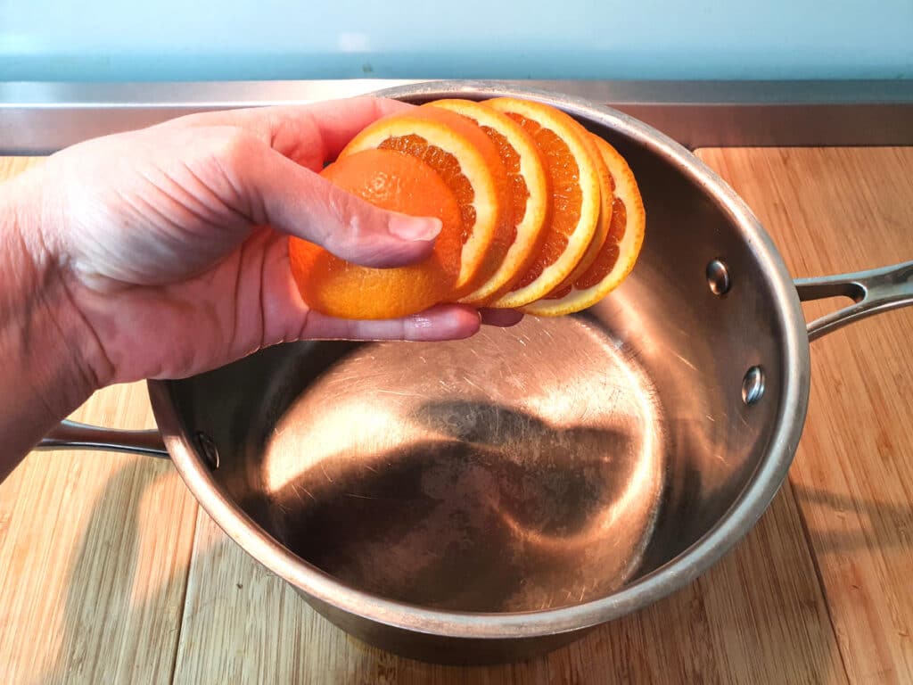 Adding sliced oranges to pot.