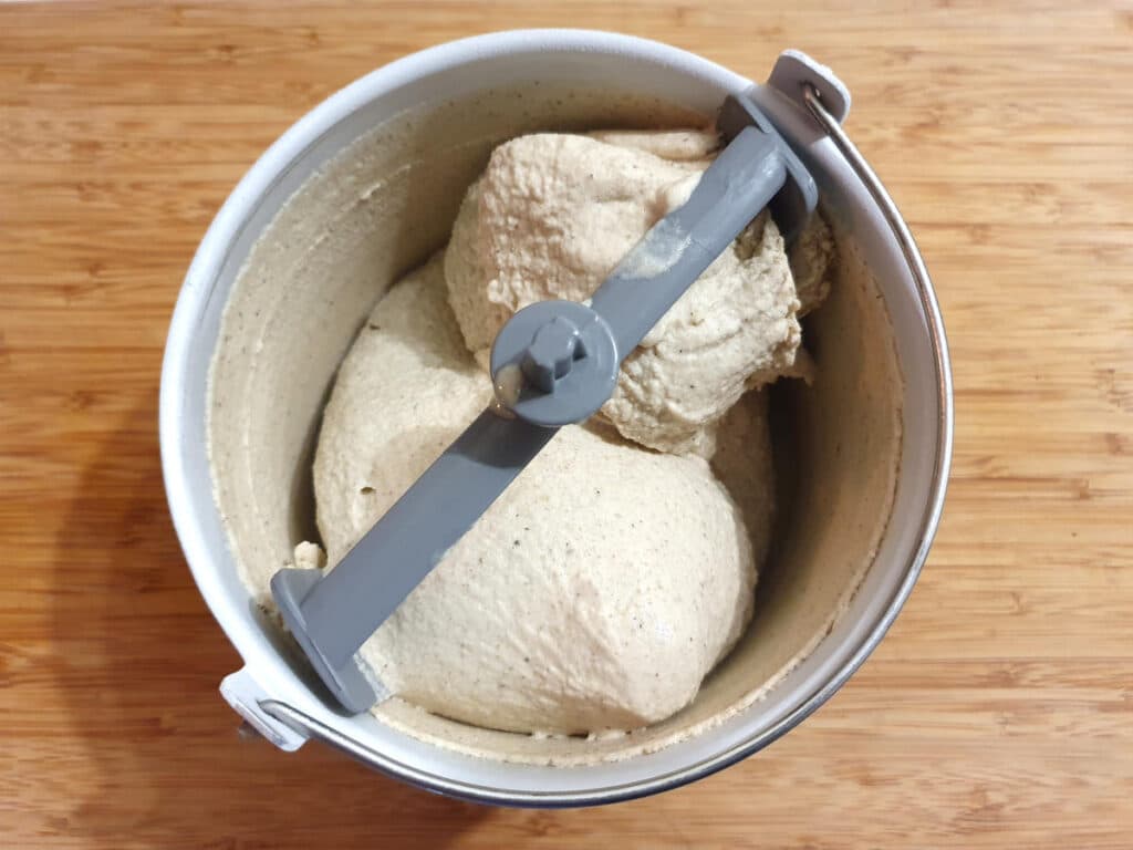 top down view of churned ice cream in ice cream churner bucket, on a chopping board.