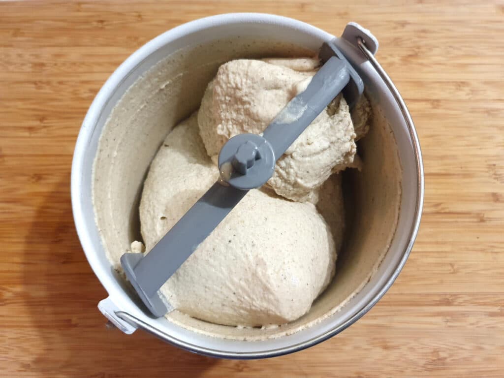 Banana ice cream 15 top down view of churned ice cream in ice cream churner bucket, on a chopping board.
