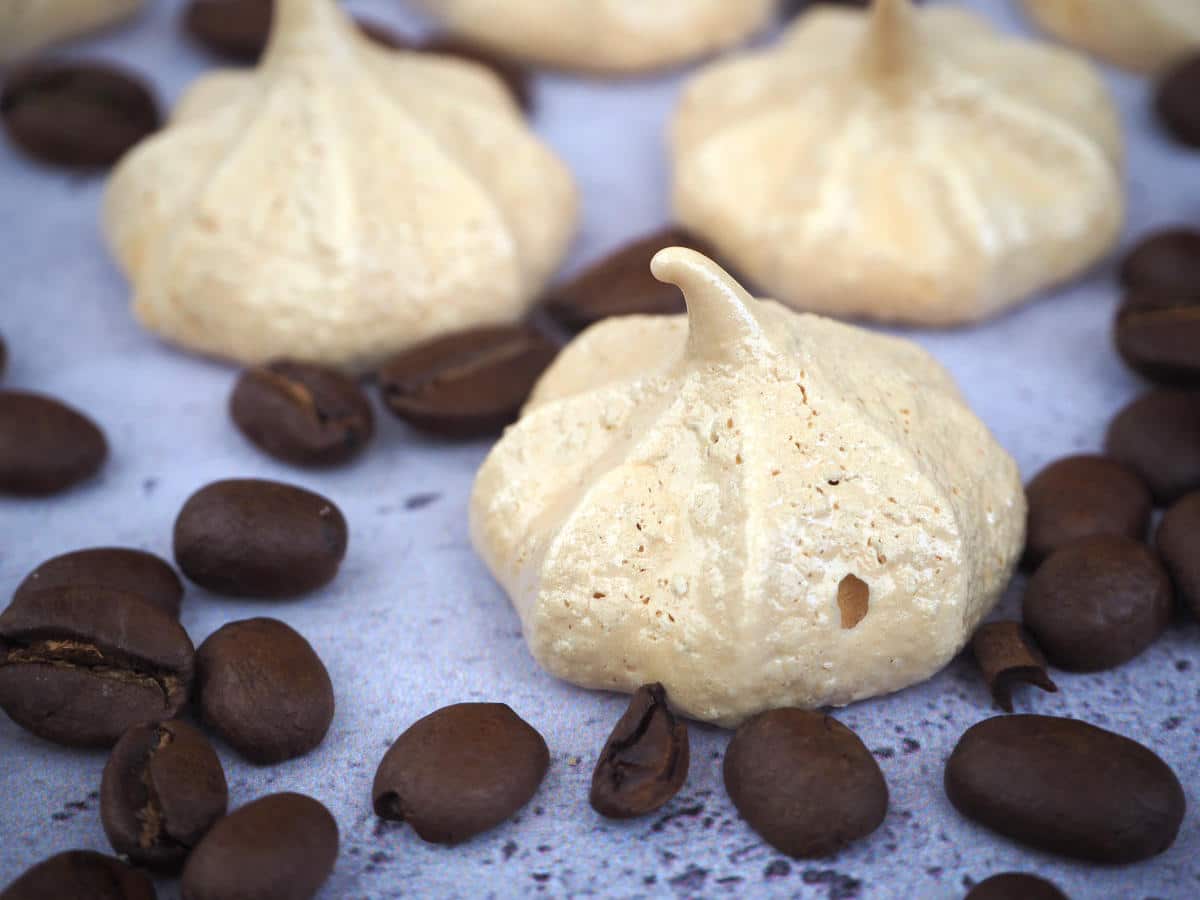 side view close up of coffee aquafaba meringues with coffee beans, on a grey background.