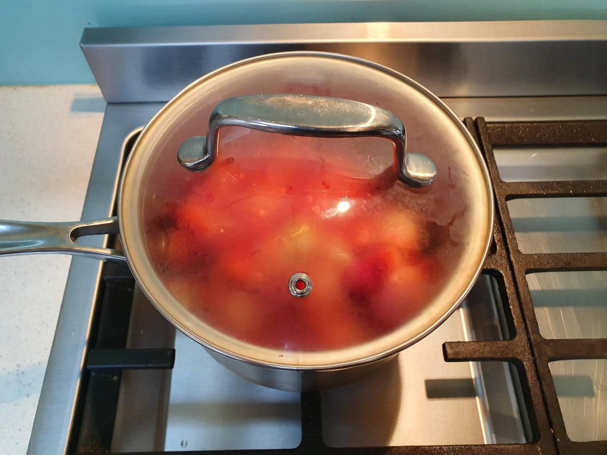 strawberry sauce in pot on stove with lid on.