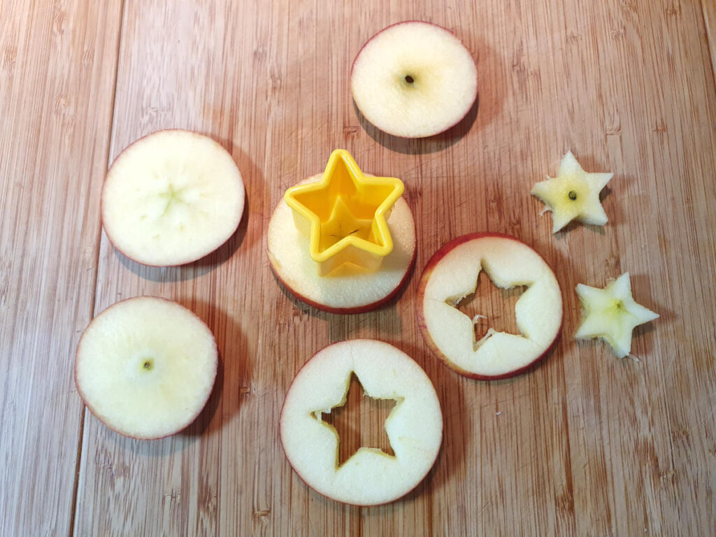 Mulled apple cider 5 slicing up apples and cutting out small apple stars using a star cookie cutter.