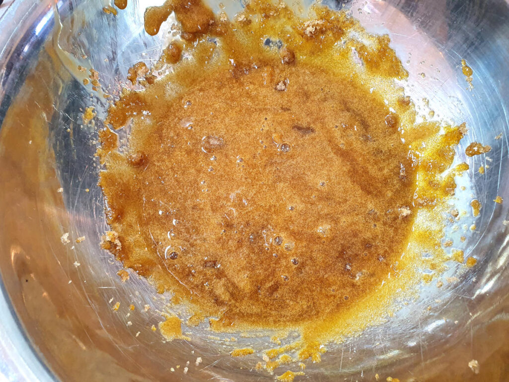 Pumpkin spice ice cream 15 top down view starting to blend brown sugar and egg yokes, in a metal bowl.