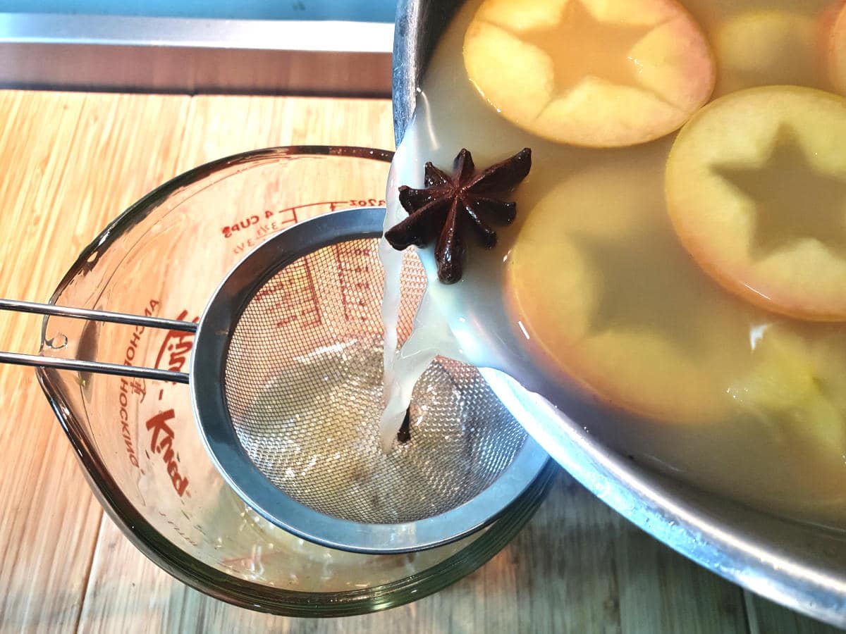 straining cooled apple cider through a sieve into a heat proof jug.