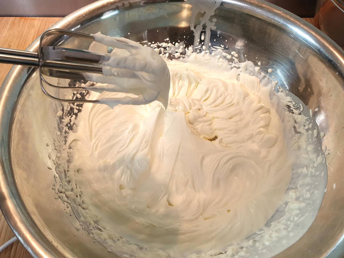 whipping cream into soft peaks using electric hand held beaters.