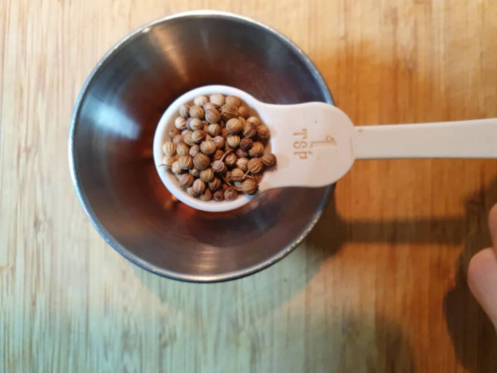 measuring corriander seeds into a small bowl.