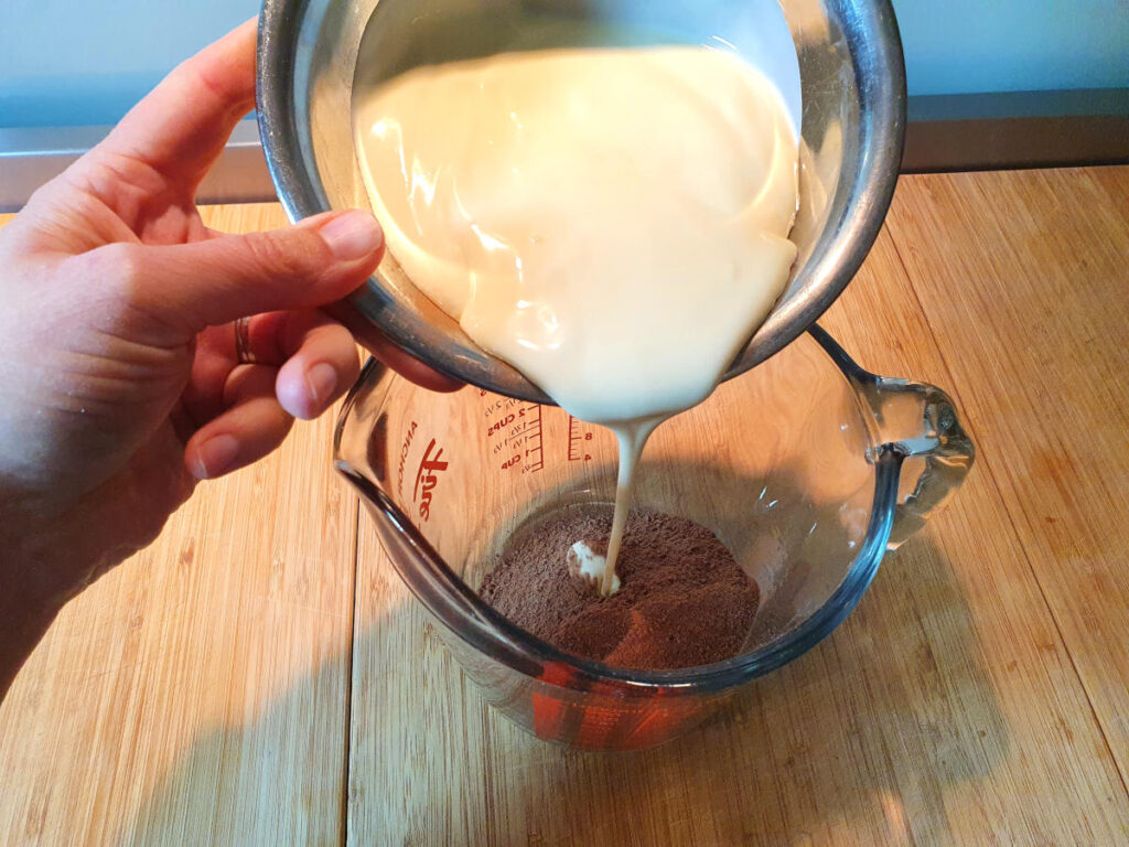 adding cream to jug with milo.