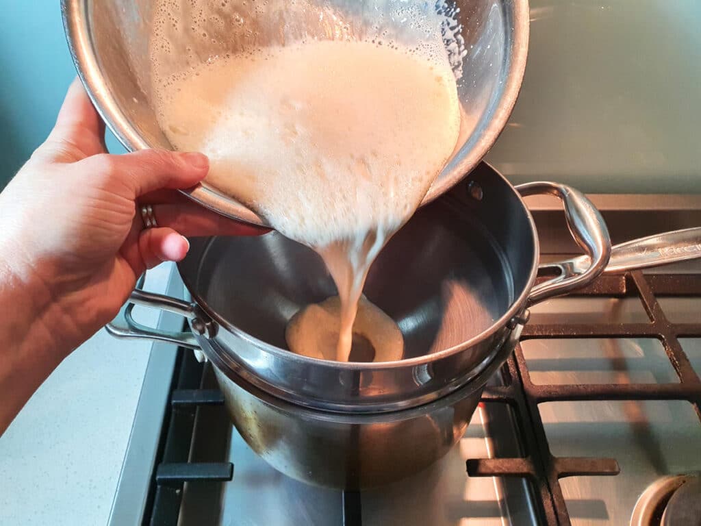 Adding egg yoke, sugar and milk mix to double boiler on stove.