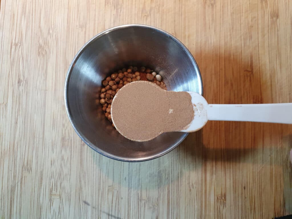 Homemade cola 11 Measuring kola nut powder into a small bowl.
