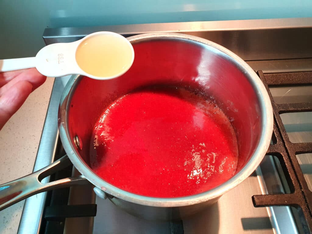 adding lemon juice to strawberry mix in pot.