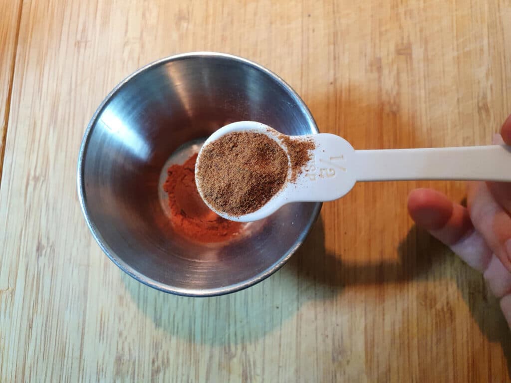 Measuring nutmeg into a small bowl.