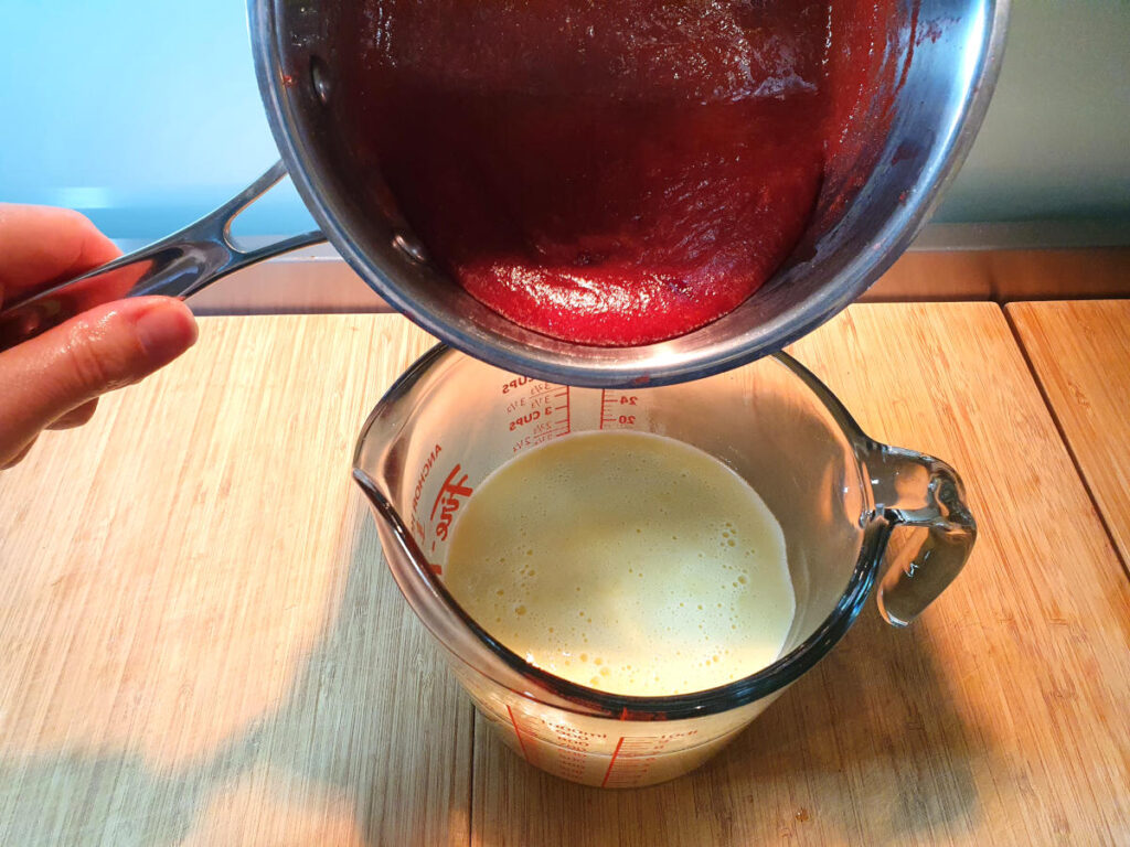 adding strawberry mix to ice cream base in heat proof jug.