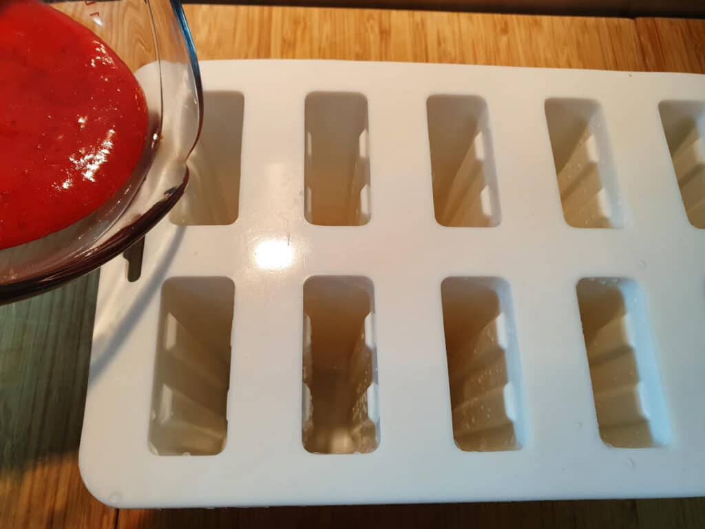 Add first layer of strawberry mix to popsicle molds.