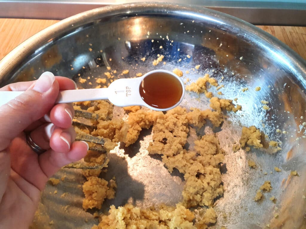 adding vanilla to beaten white and brown sugar and butter, in a large metal mixing bowl.