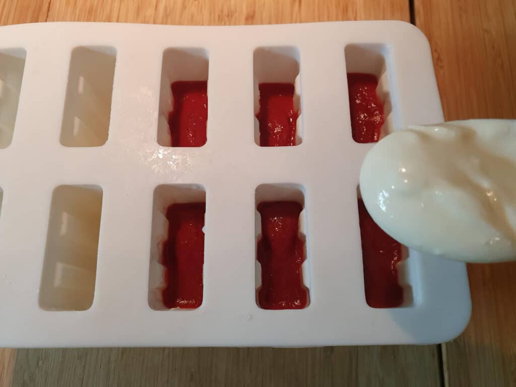 adding top yogurt layer to popsicle molds.