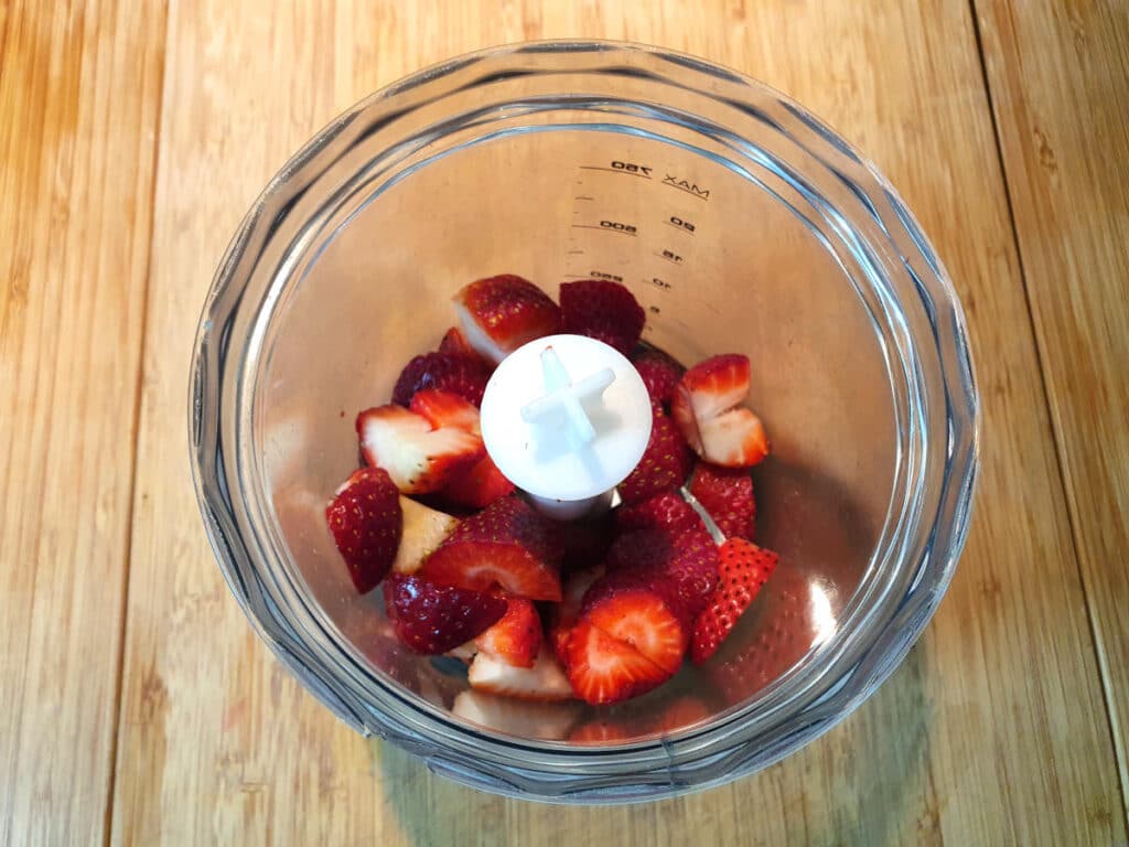 strawberry pieces in mini food processor ready to blitz.