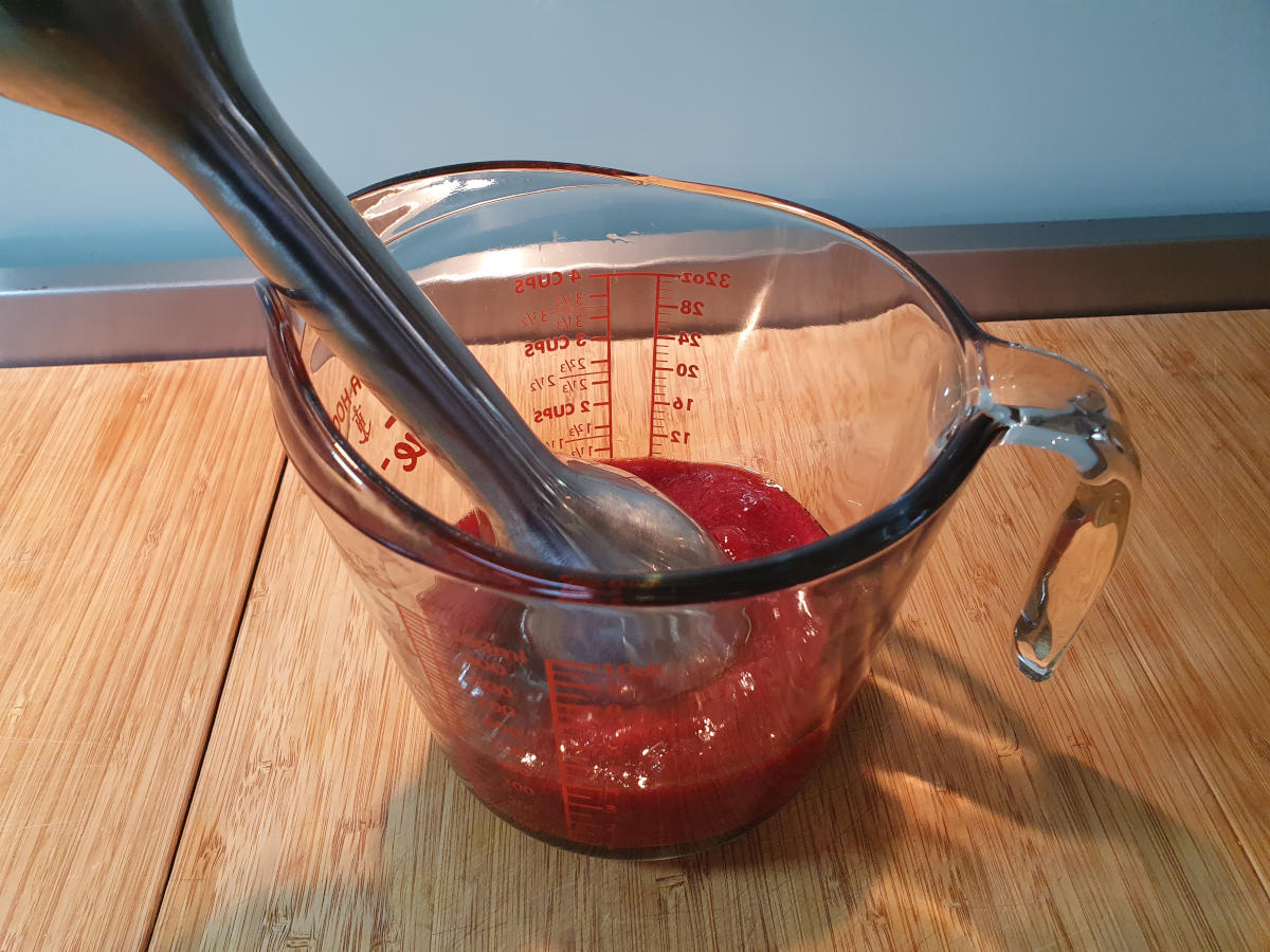 blitzing cooked strawberries with an immersion blender in a jug.