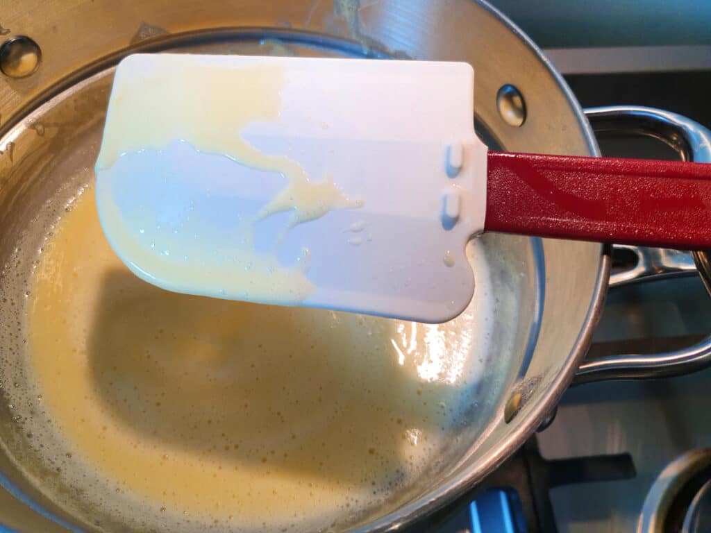 Strawberry ice cream 11 checking custard to for doneness, custard is sticking to spadular with visable line in it after running your finger through it.